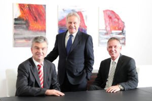 GD Windtner, VD Steinecker und VD Kolar im Büro vor drei Gemälden