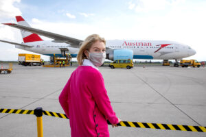 Christine Haberlander am Flughafen in Linz vor einem Flieger von Austrian Airlines
