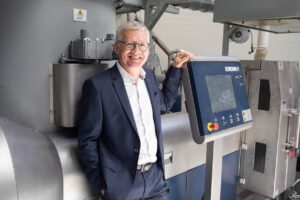 EREMA CEO Manfred Hackl an einer Maschine lehnend