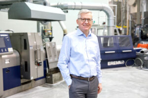 EREMA CEO Manfred Hackl in der Werkstatt neben einer Maschine