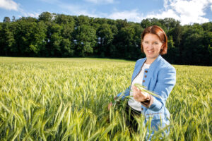 LR Michaela Langer-Weninger in der Natur mit Gerstenhalm in der Hand