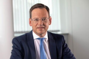 GD Klaus Kumpfmüller vor einem Fenster mit Vorhängen