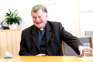 Bischof Manfred Scheuer lachend im Gespräch in seinem Büro