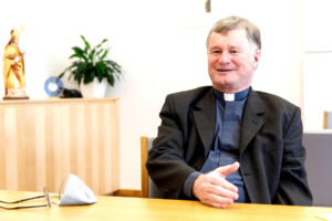 Bischof Manfred Scheuer in seinem Büro im Gespräch mit Pflanzen im Hintergrund