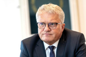 Klaus Luger in einem ernsten Gespräch vor einem dunklen Gemälde