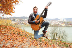 Musiker Andie Gabauer mit Gitarre in der Natur