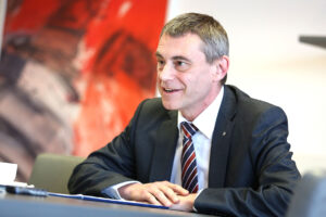 GD Heinz Schaller im Interview mit rotem Gemälde im Hintergrund
