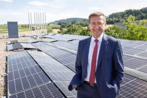 LR Achleitner auf einem Hausdach mit Solarpanel im Hintergrund